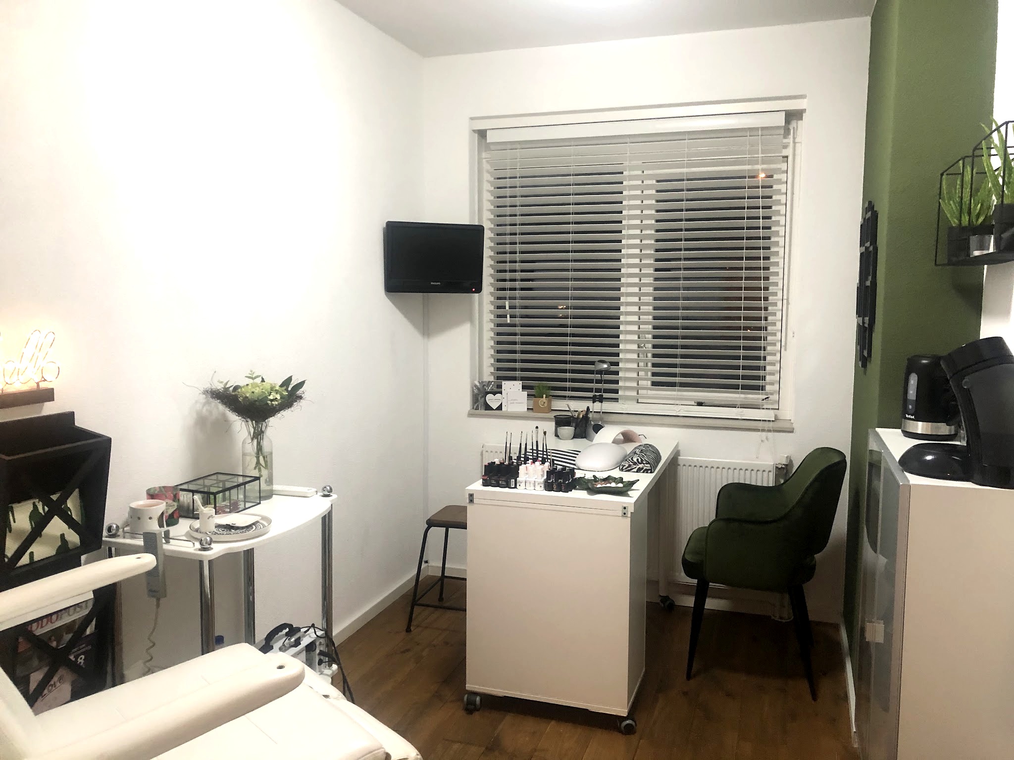 Overzicht van de salon met de pedicurestoel, de nageltafel en het raam met jaloezieën