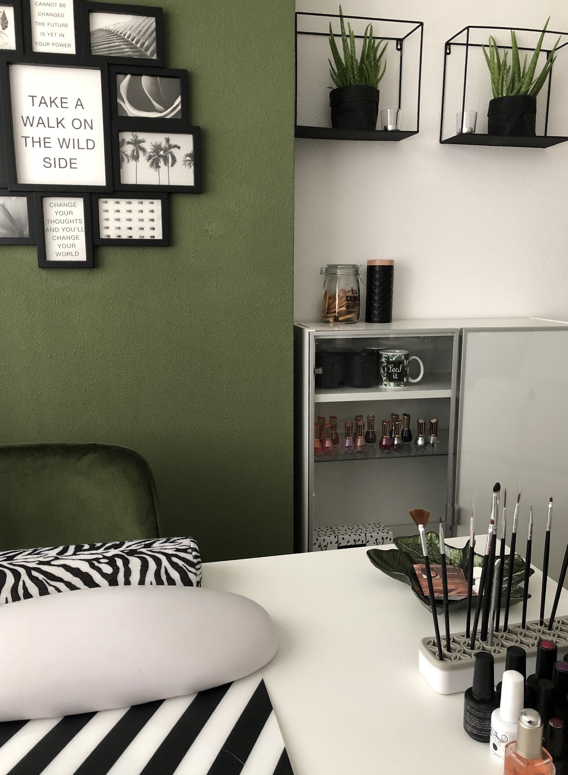 De nageltafel in de salon: gellakken, penselen en lijstjes aan de groene wand